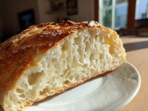 Close-up of the open, airy crumb structure of a slice of amazing Italian bread with a golden crust.
