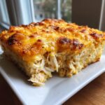 A close-up serving of cheesy chicken and rice casserole with a golden brown, bubbly cheese topping.