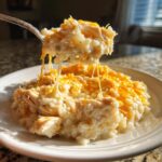 A fork lifts a cheesy, creamy bite of crock pot chicken and rice, showing melted cheese strings.
