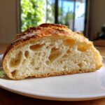 Close-up of the open crumb structure of a slice of amazing Italian bread showing large air pockets.