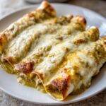 Close-up of three delicious green chile chicken enchiladas covered in melted cheese.