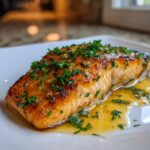 A perfectly cooked, glazed honey garlic salmon fillet topped with fresh chopped parsley, resting in its sauce.