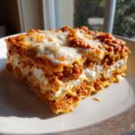 A thick, layered slice of lasagna with cottage cheese and meat sauce, perfectly baked.