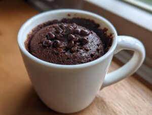 Close-up of a freshly baked chocolate mug cake topped with chocolate chips inside a white mug.