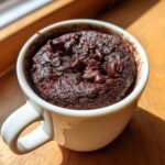 Close-up of a rich, dark chocolate mug cake topped with melted chocolate chips, ready to eat.