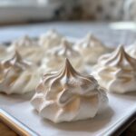 Close-up of perfectly piped white meringue cookies on a baking sheet, ready to bake.