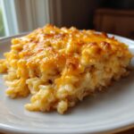 A close-up serving of creamy, baked cheesy rice topped with a layer of golden, melted cheddar cheese.