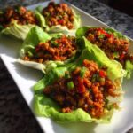 Close-up of several flavorful chicken lettuce wraps filled with savory ground chicken mixture, garnished with green onions.