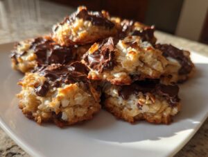 A close-up stack of freshly baked almond joy cookies featuring toasted coconut and melted chocolate topping.