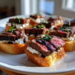 Close-up of several perfectly cooked steak crostini bites topped with creamy cheese and balsamic glaze.