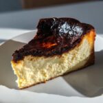 A close-up slice of creamy Basque cheesecake featuring its signature dark, caramelized top.