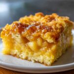 Close-up of a moist slice of caramel apple dump cake showing tender apples and gooey caramel topping.
