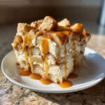 A decadent slice of caramel apple trifle layered with cream, cake, and topped with dripping caramel sauce.