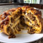 Cross-section of cheesy garbage bread showing melted cheese stretching between layers of seasoned ground meat filling.