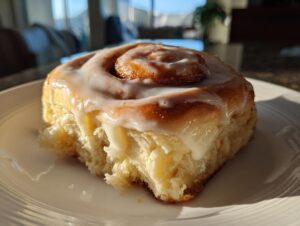 Close-up of a single, fluffy cinnamon roll with thick white icing, perfect for cinnamon rolls with heavy cream recipes.