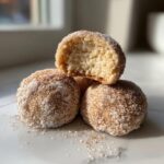 Three delicious cinnamon sugar snowball cookies stacked, with the top one broken open showing the soft interior.