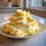 A generous mound of creamy, pale yellow Boursin mashed potatoes served on a white plate.