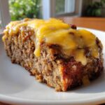 A close-up slice of moist crockpot french onion meatloaf topped with melted yellow cheese.