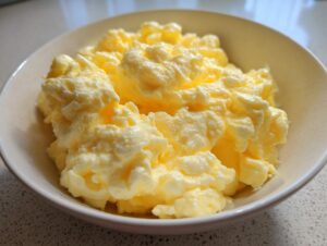 Close-up of incredibly fluffy scrambled eggs served in a light-colored bowl.