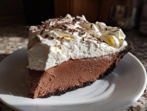 A generous slice of rich french silk pie featuring a dark chocolate filling and thick whipped cream topping.
