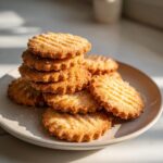 A stack of golden brown, ridged butter cookie treats sprinkled with sugar, resting on a light plate.