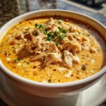A close-up of a rich, creamy bowl of instant pot white chicken chili topped with shredded chicken and green onions.