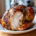 Close-up of a perfectly roasted turkey with a slice cut out, revealing moist white meat and a seasoned, crispy skin.