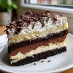 A decadent slice of layered Italian love cake featuring chocolate cake, mousse, cream, and topped with whipped cream and dark chocolate shavings.