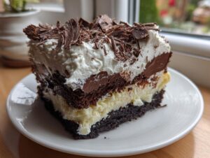 A rich, layered slice of italian love cake featuring chocolate cake, cream, and topped with whipped cream and dark chocolate shavings.