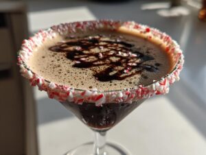 Close-up of a peppermint espresso martini with a crushed candy cane rim and chocolate drizzle.
