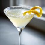 Close-up of a chilled lemon drop cocktail in a martini glass with a sugared rim and lemon twist garnish.