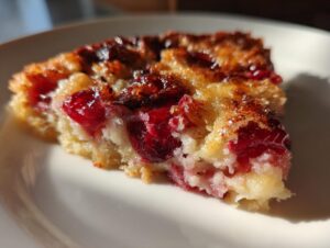 Close-up of a moist slice of cherry dump cake showing bright red cherries baked into a golden, slightly caramelized cake base.