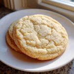 Close-up of two delicious soft sugar cookies stacked on a white plate, coated in sparkling sugar crystals.