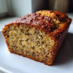 A close-up of a moist slice of sourdough banana bread with a dark, caramelized top crust.