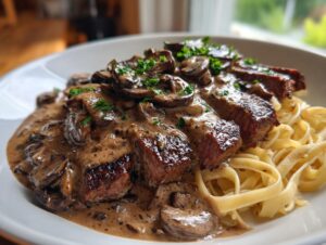 Slices of seared steak generously covered in a rich mushroom sauce and served over fettuccine pasta.